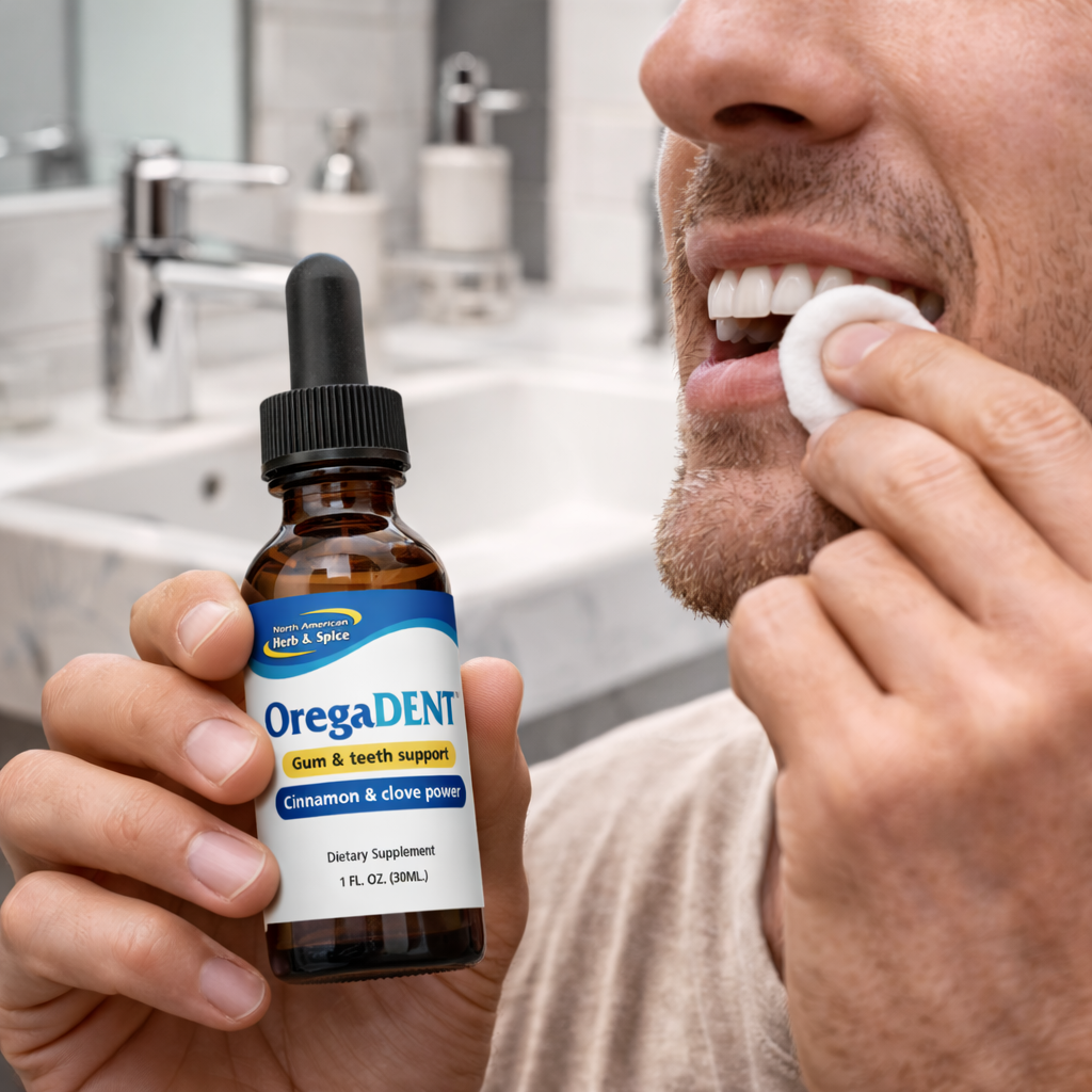 Man in a bathroom holding OregaDENT while pressing a cotton pad to his gums.